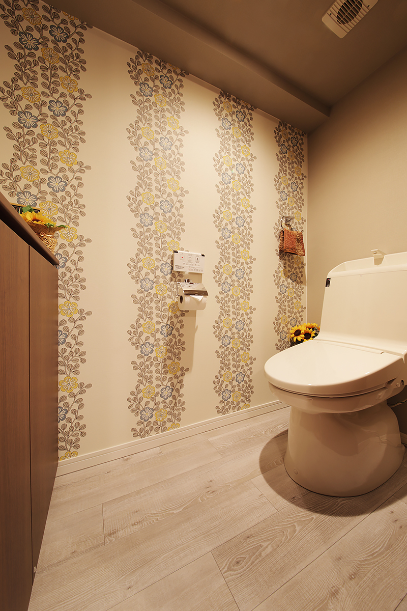 トイレの床もフローリングに。壁には植物柄のアクセントウォールを採用。