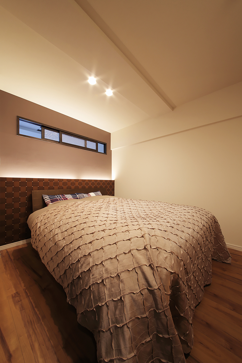 ベッドの頭側につくった壁に間接照明を入れて安らげる空間に。寝室と玄関側の土間から出入りできるウォークインスルークローゼットがあります。