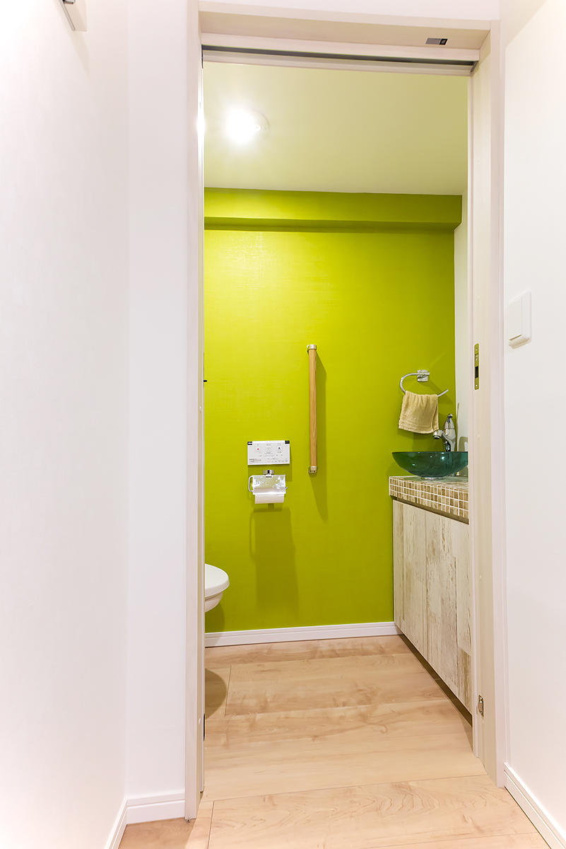 狭い空間だからこそ、快適性を追求したトイレ。壁の一面は一番好きなライトグリーンにし、ガラス製の手洗いボウルとの相性も◎。介護用の手すりも装備。