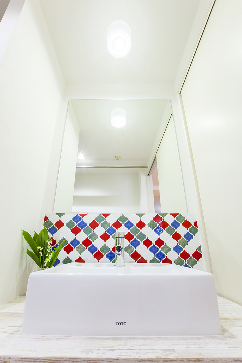 白を貴重とした洗面スペース。デザインタイルが遊び心のある空間を演出。