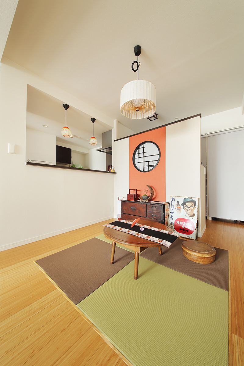 畳の空間にオレンジ色を取り入れて、より印象的な空間に。丸窓のある仕切り壁の後ろにカウンターデスクと収納棚を設けた趣味部屋を。