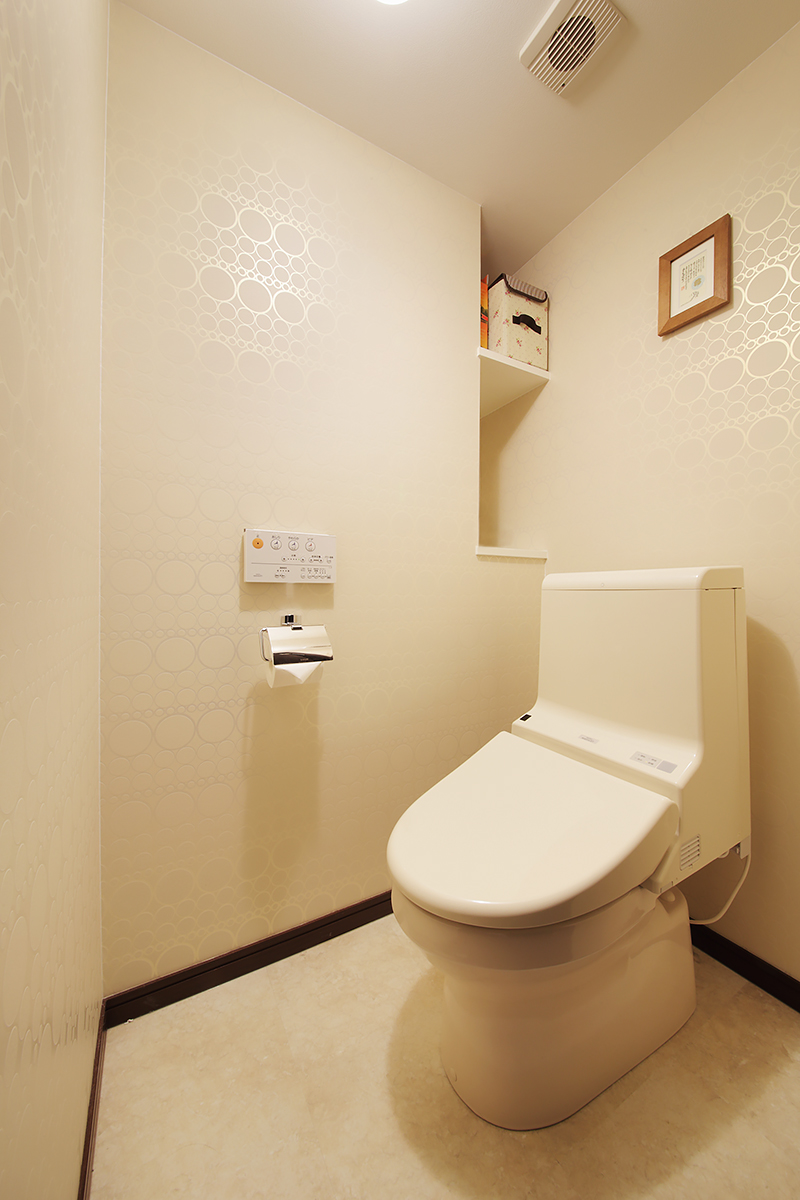 目につかないトイレの壁も地紋入りのクロスやデザイン性の高いペーパーホルダーでお洒落に演出。ちょっとした収納棚があるのも便利。