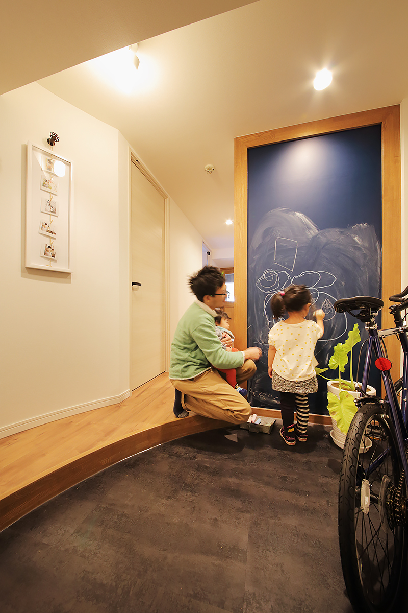 ベビーカーや自転車が置ける玄関土間。黒板塗装で仕上げた壁は大きな"お絵描きボード"。