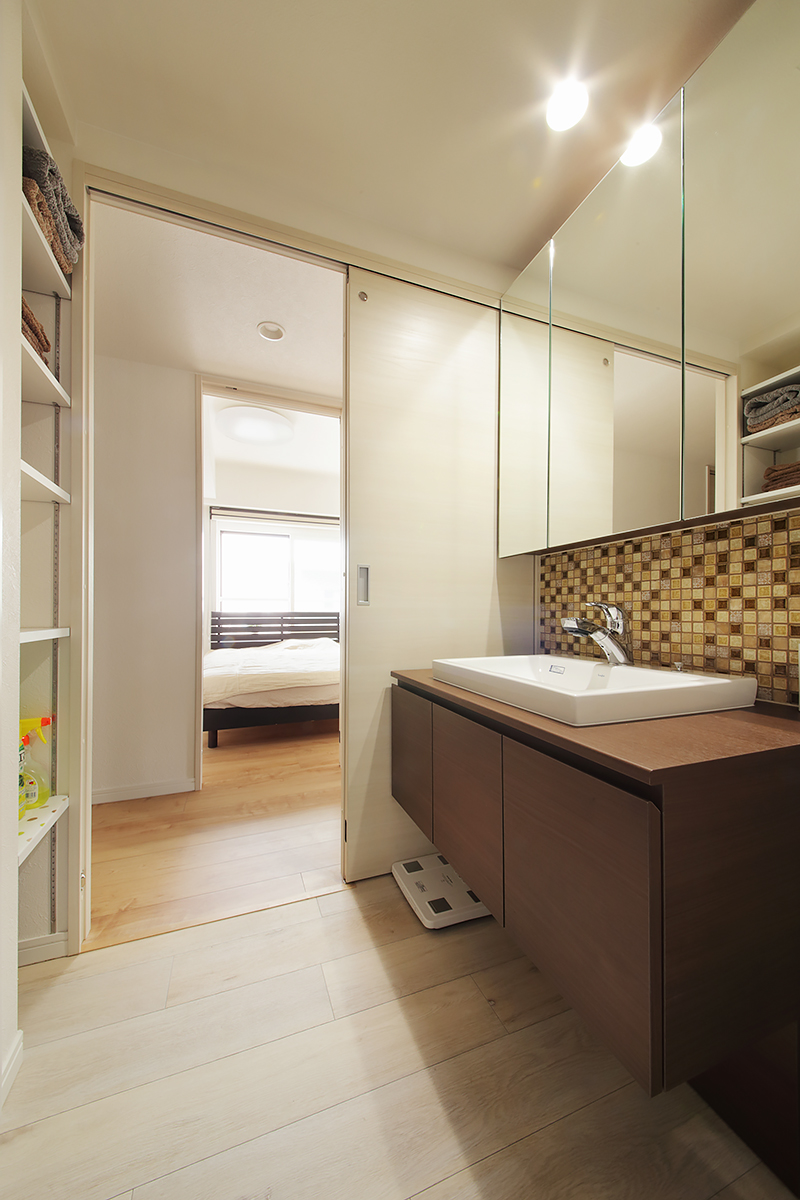 アンティーク調のガラスタイルを使った洗面スペースは、背後の壁にも収納棚を設け、タオルや洗剤をすっきり収納。