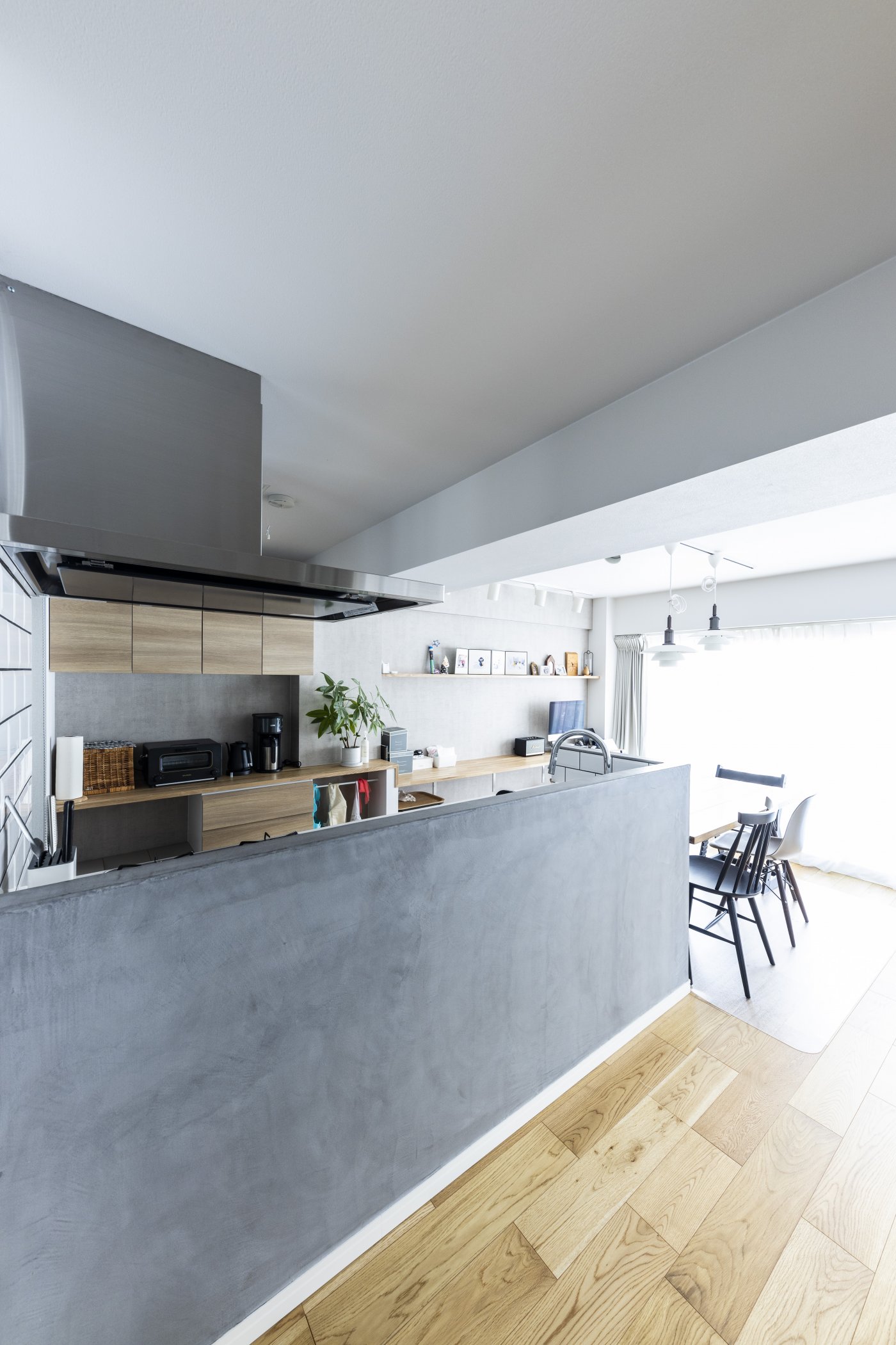 腰壁がモルタルのような質感のかっこいいキッチン。シンク側はタイル仕上げ。冷蔵庫やレンジボードはパントリー内に収めてキッチンをすっきりと。